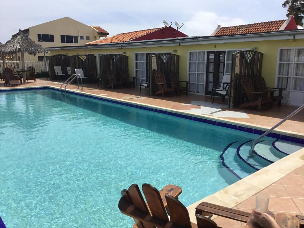 棕榈滩阿鲁巴昆库公寓式酒店的一座带椅子的大型游泳池,位于大楼旁