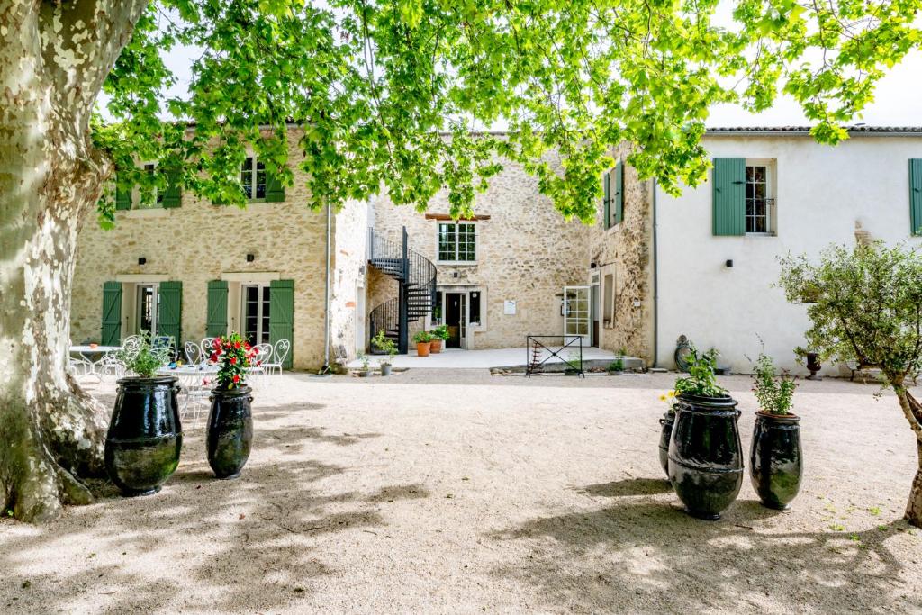 马洛塞讷Hôtel & SPA Ventoux Provence "Domaine des Tilleuls"的一群满是鲜花的黑色容器,在建筑物前