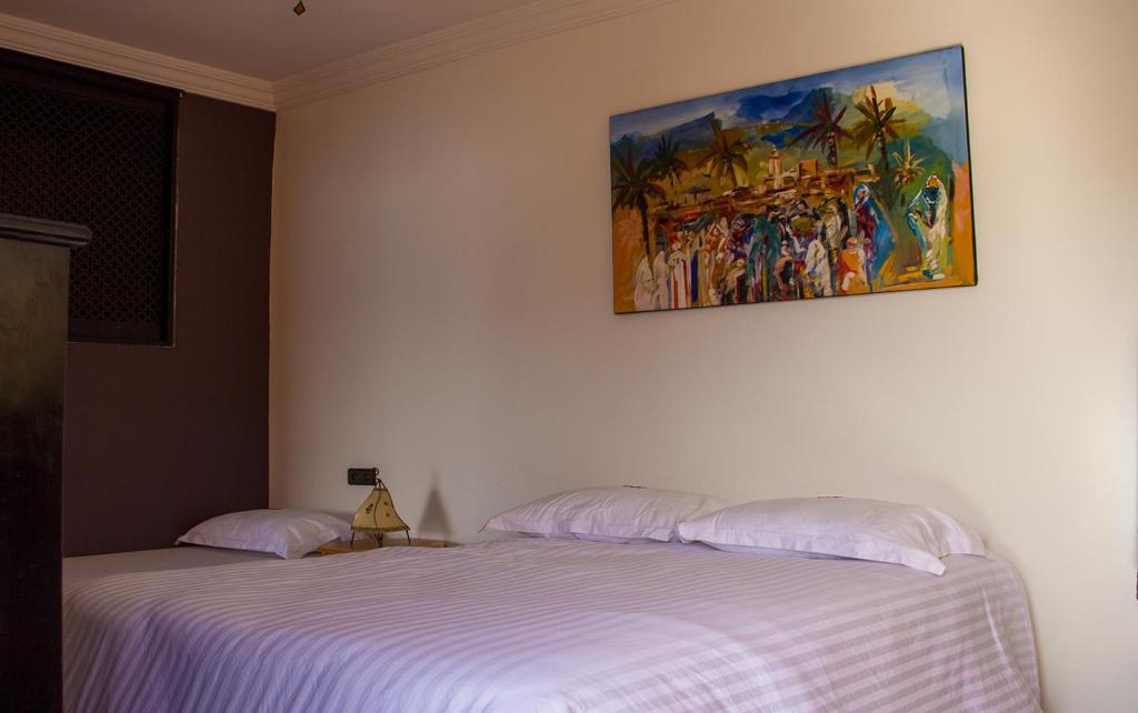 依索安Peak House Imsouane的一间卧室设有两张床,墙上挂着一幅画