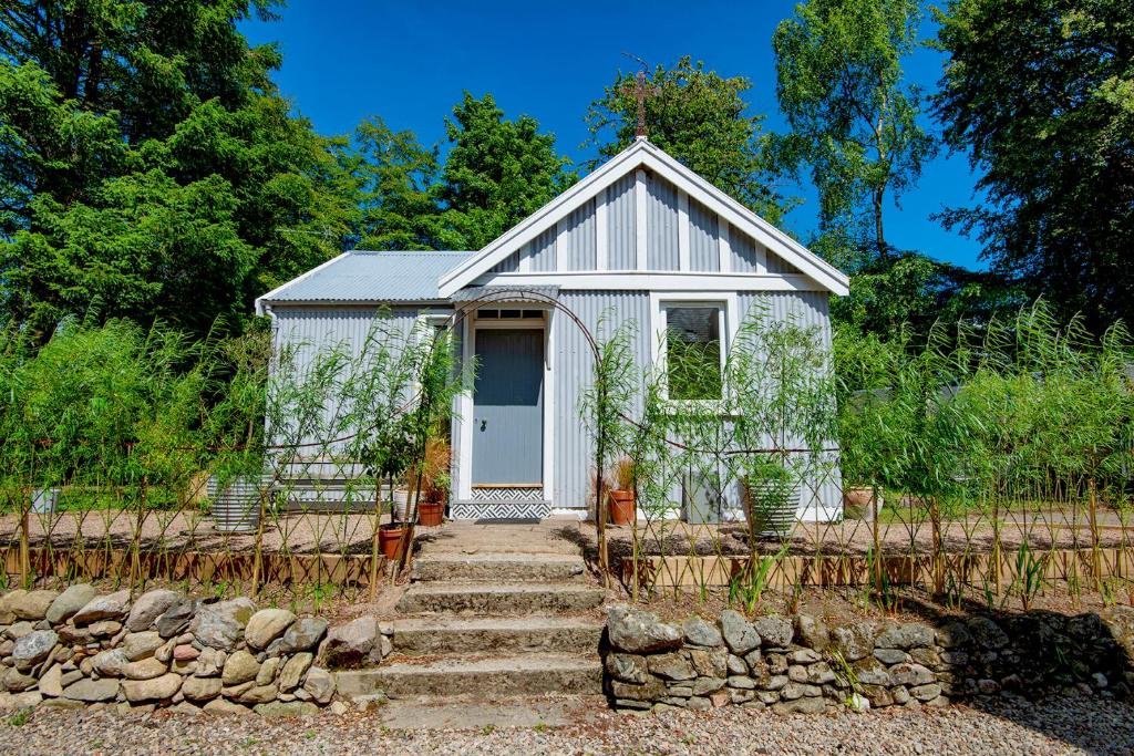 GlenogilTin Cabin in peaceful Angus glen的一座白色的小房子,设有通往房子的楼梯