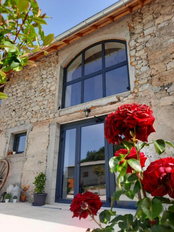 Saint-Auban-dʼOzeLe Petit Bégou的一座石头建筑,设有窗户和红色玫瑰