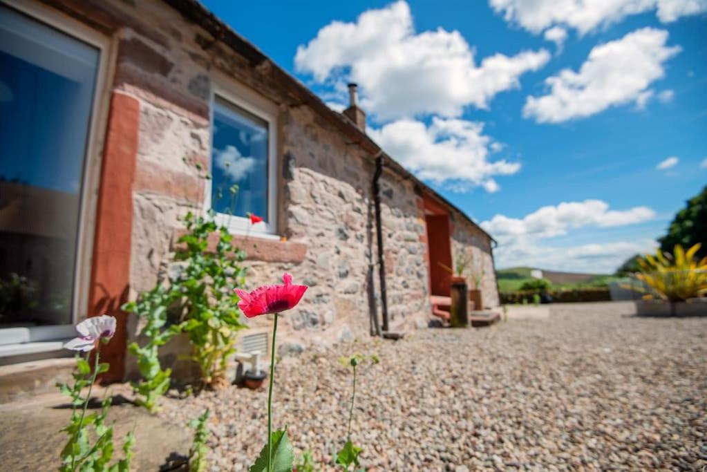弗福尔Spacious & Stylish StoneHous Cottage的一座石头建筑,前面有鲜花