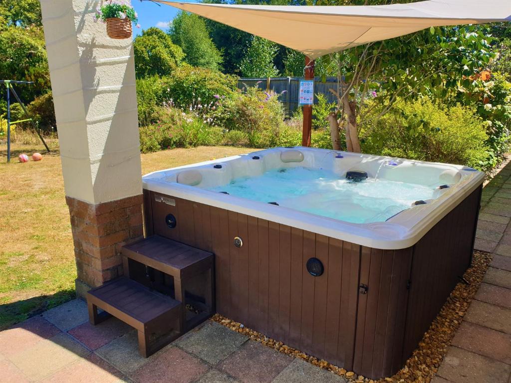 灵伍德Lions Lodge: Great location with hot tub的一个带凳子的伞下按摩浴缸