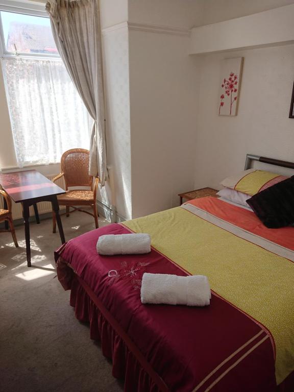布莱克浦Fernlea Hotel的一间卧室配有两张床、一张桌子和一张桌子