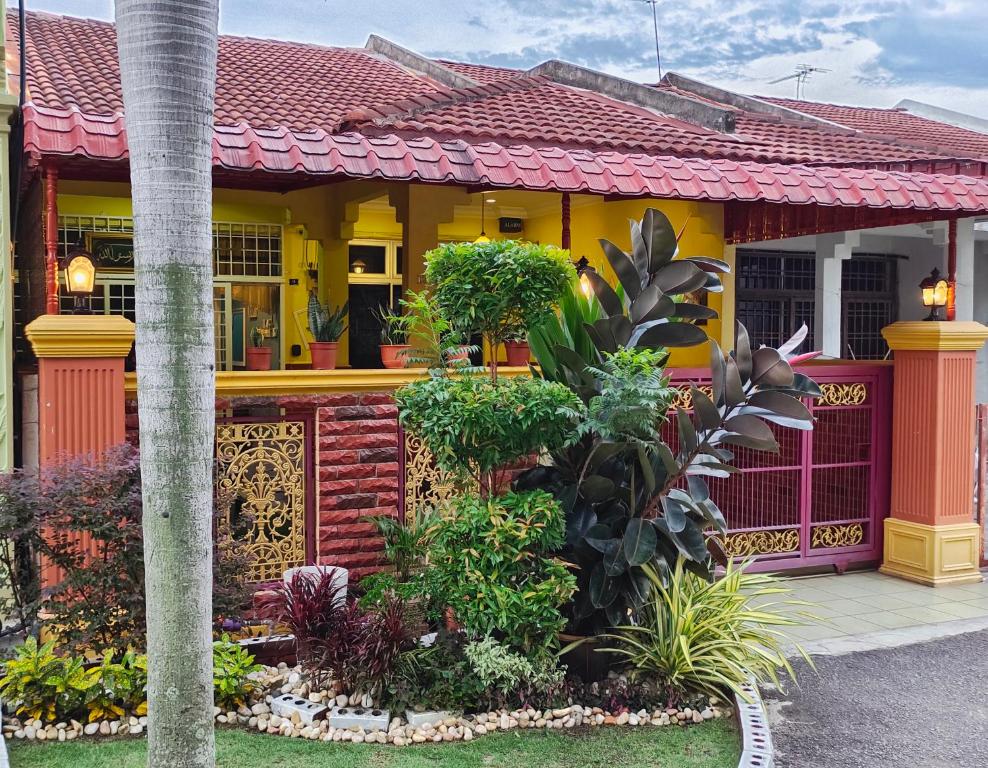 Kampong Bukit KatilFaridah Homestay Melaka Muslim Friendly的一座黄色和红色的房子,前面有植物