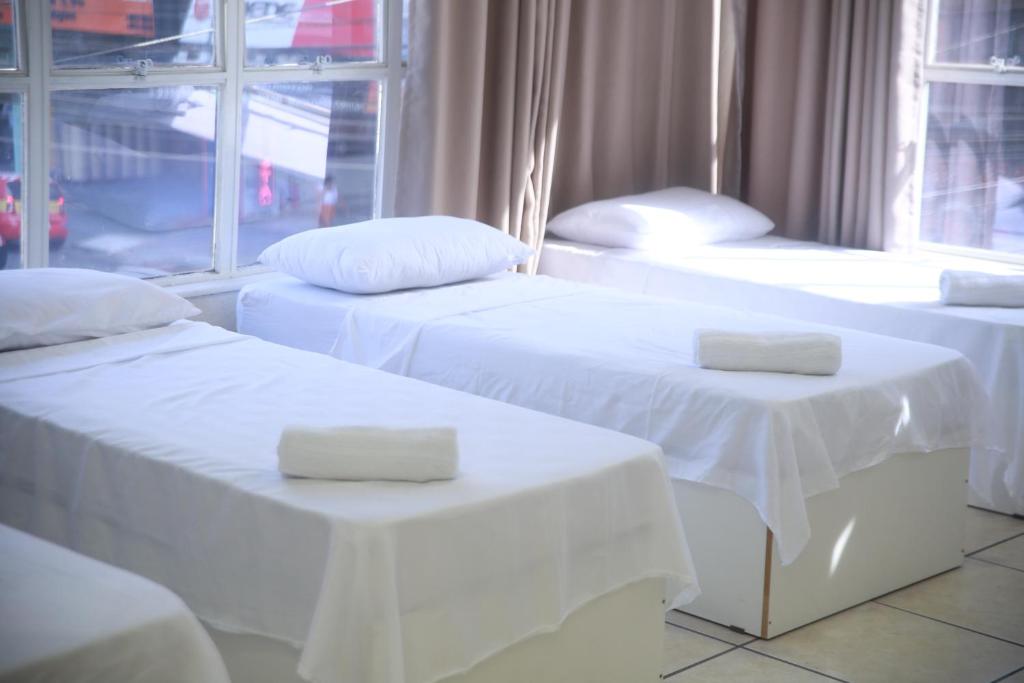 圣贝尔纳多-杜坎普Hotel Jurubatuba的带窗户的客房内的3张带白色床单的床