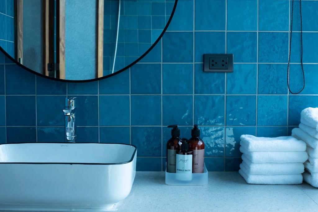 曼谷karaarom hotel的浴室设有水槽、镜子和蓝色瓷砖