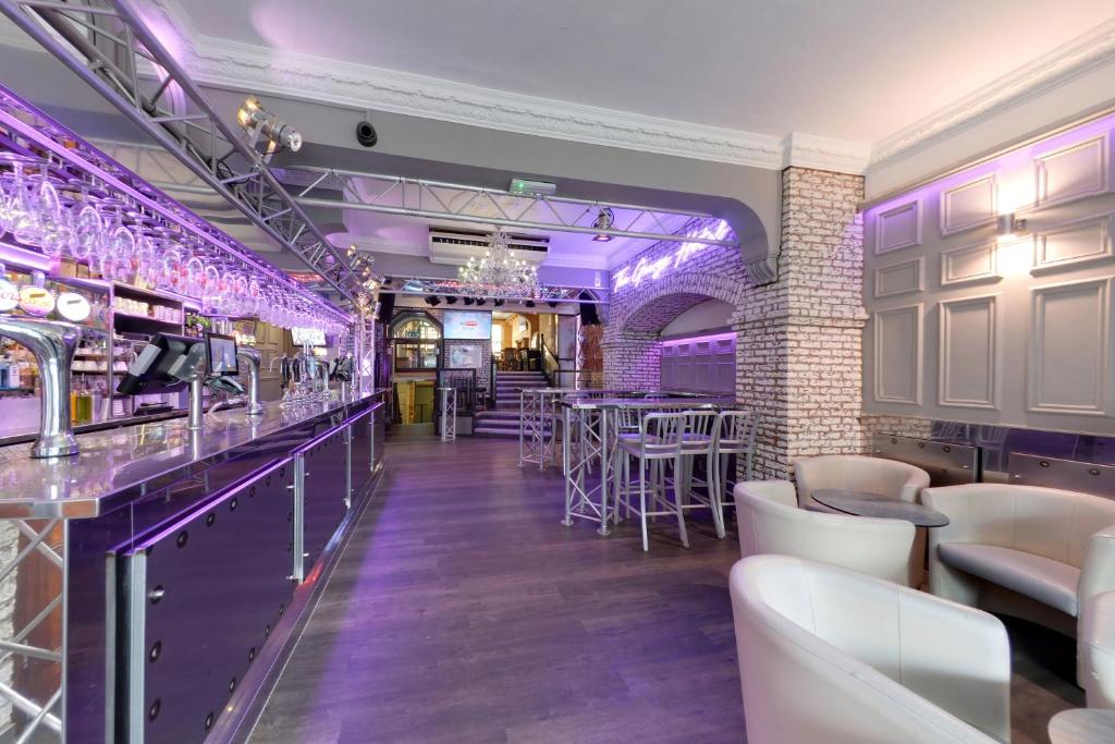 惠特比乔治酒店 的一间酒吧,配有紫色灯光和桌椅