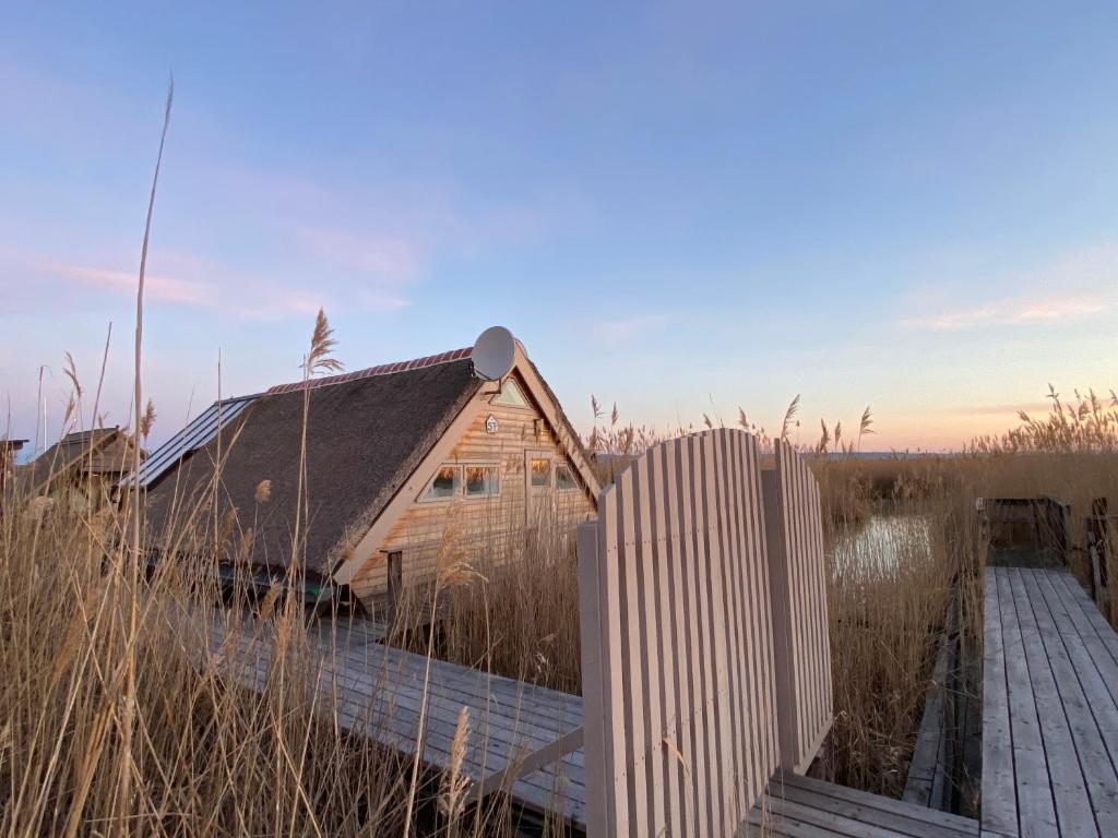 拉斯特Pfahlbau Neusiedlersee - Waterfront - erste Reihe的田野上码头上的木屋