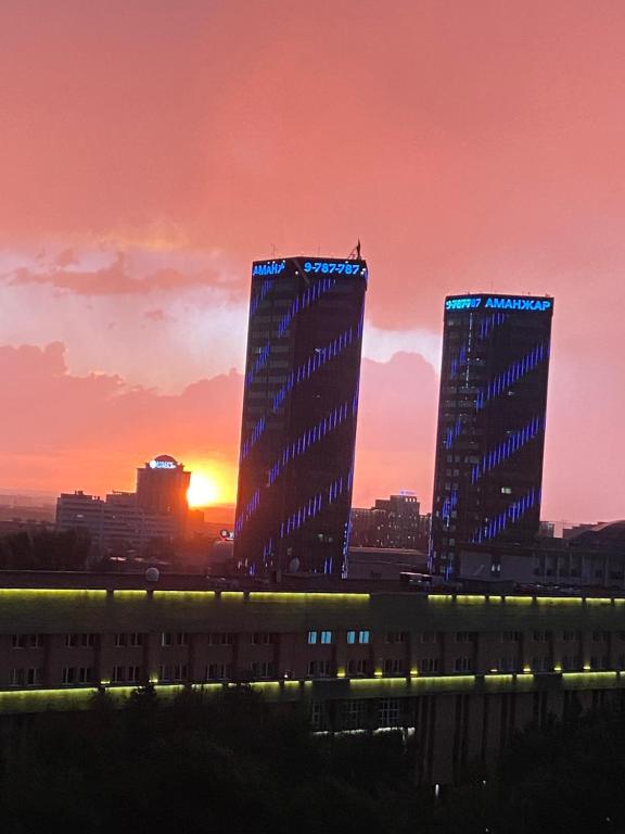 阿拉木图Квартира в центре Алматы的日落时分城市的两座高楼