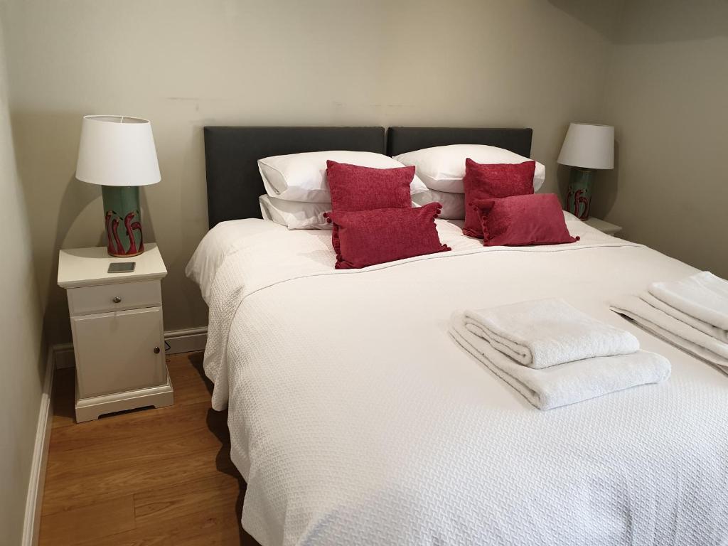 泰特伯里Trouble House的卧室配有带红色枕头的大型白色床