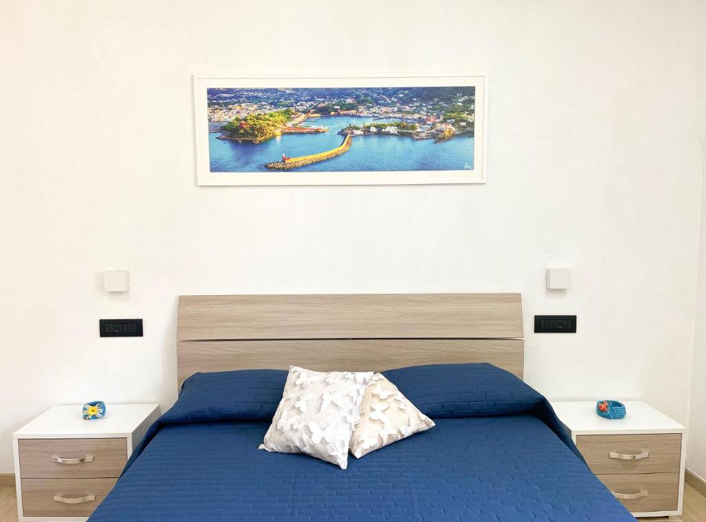 伊斯基亚Maison Marinella的卧室配有蓝色的床,墙上挂着一幅画