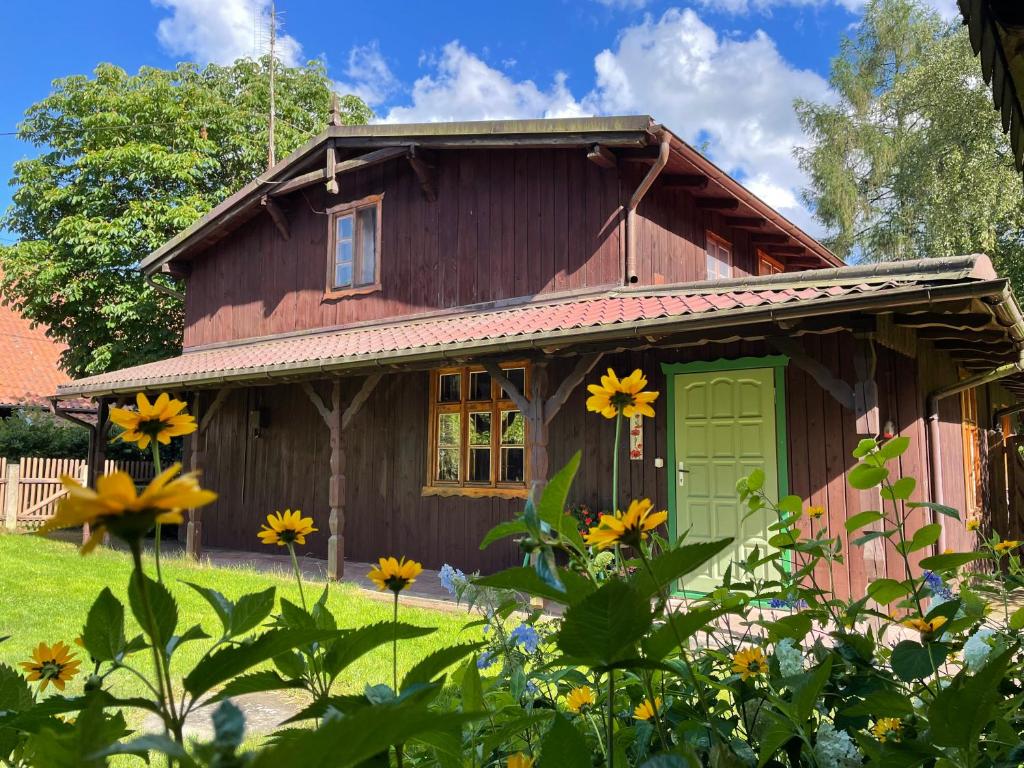 DługieChatka mojego dziadka的一座带绿门和一些鲜花的木屋