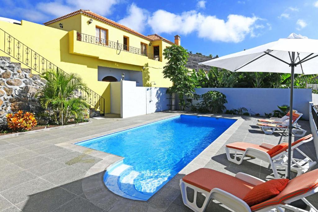 蒂哈拉费Villa Ivan的房屋旁的游泳池配有椅子和遮阳伞