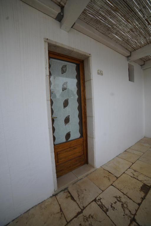 奥斯图尼Masseria Casamassima agriturismo的白色客房的木门,铺有瓷砖地板