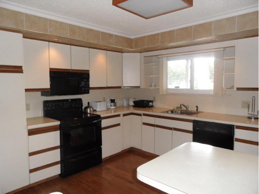 乔治湖Pinebrook - Three Bedroom House的厨房配有白色橱柜和黑色家电