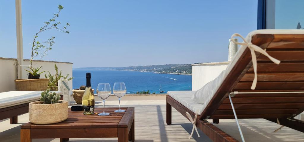 莱切省卡斯特罗Bona Vitae - Attico Vista Mare Castro的阳台配有带酒杯的桌子,享有海景
