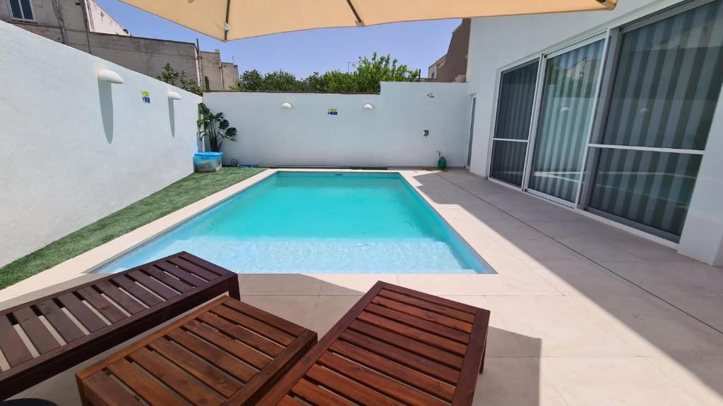 San ĠwannModern and bright 3 bedroom villa with pool.的一个带两把椅子和遮阳伞的游泳池