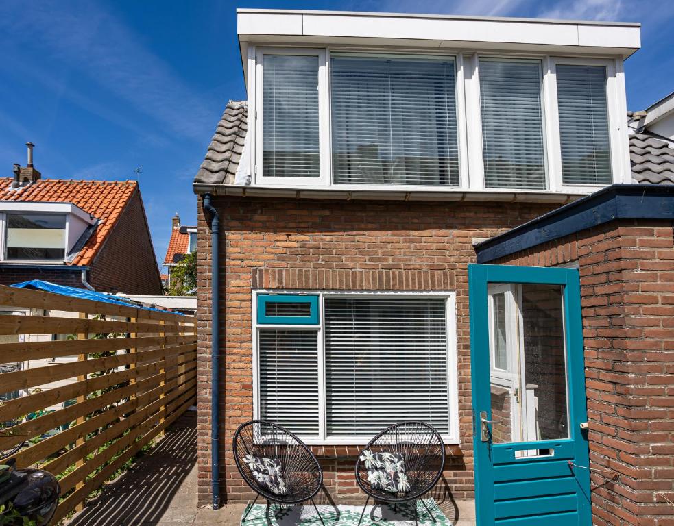 诺德韦克Tiny Beachhouse Noordwijk的一座房子,配有两把椅子和一扇蓝色的门