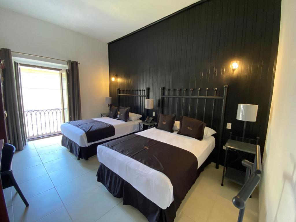 瓜纳华托Hotel Plata Condesa的酒店客房设有两张床和窗户。