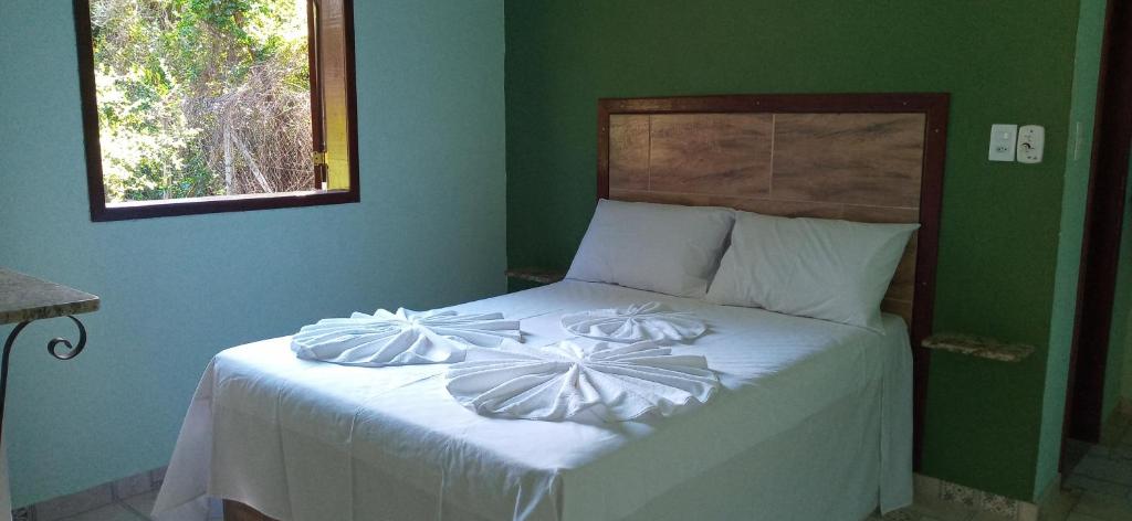西波山Chalés Jardim da Serra的一间卧室配有一张带白色床单和绿色墙壁的床。