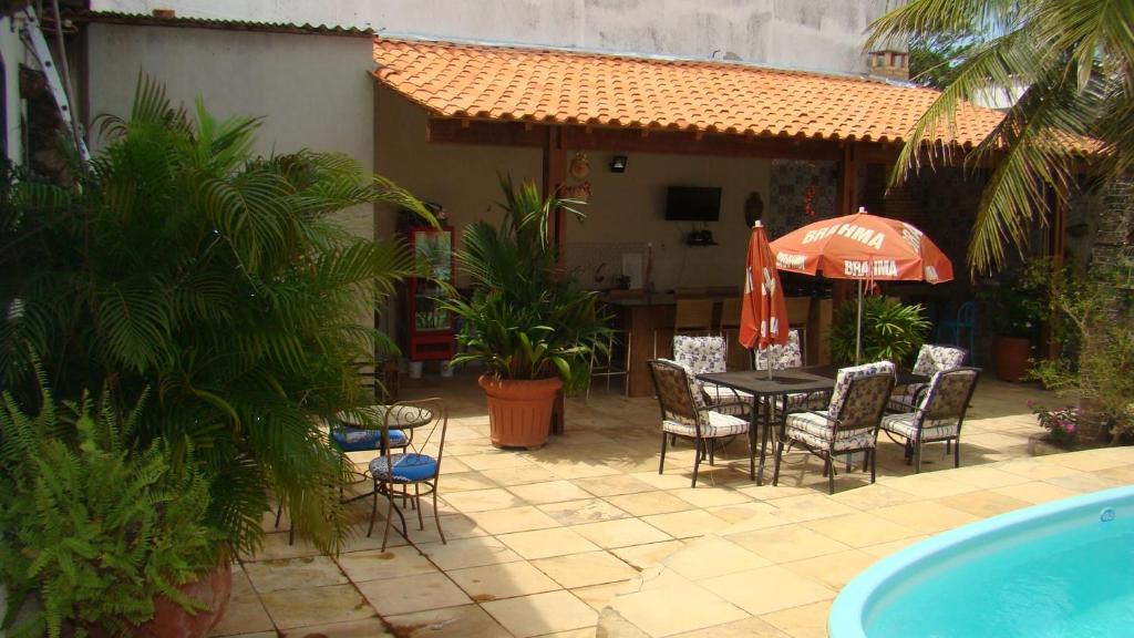 圣路易斯Casa perto da praia com piscina, churrasqueira em SLZ的庭院配有桌椅和遮阳伞。
