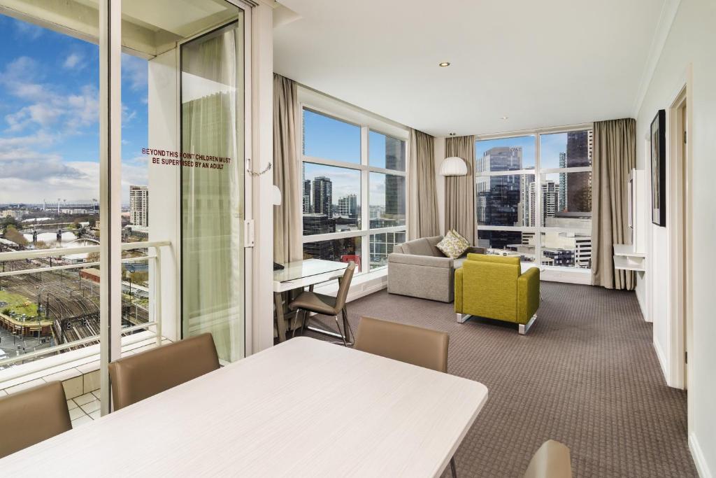 墨尔本凯隆套房酒店的客厅配有桌椅和窗户。
