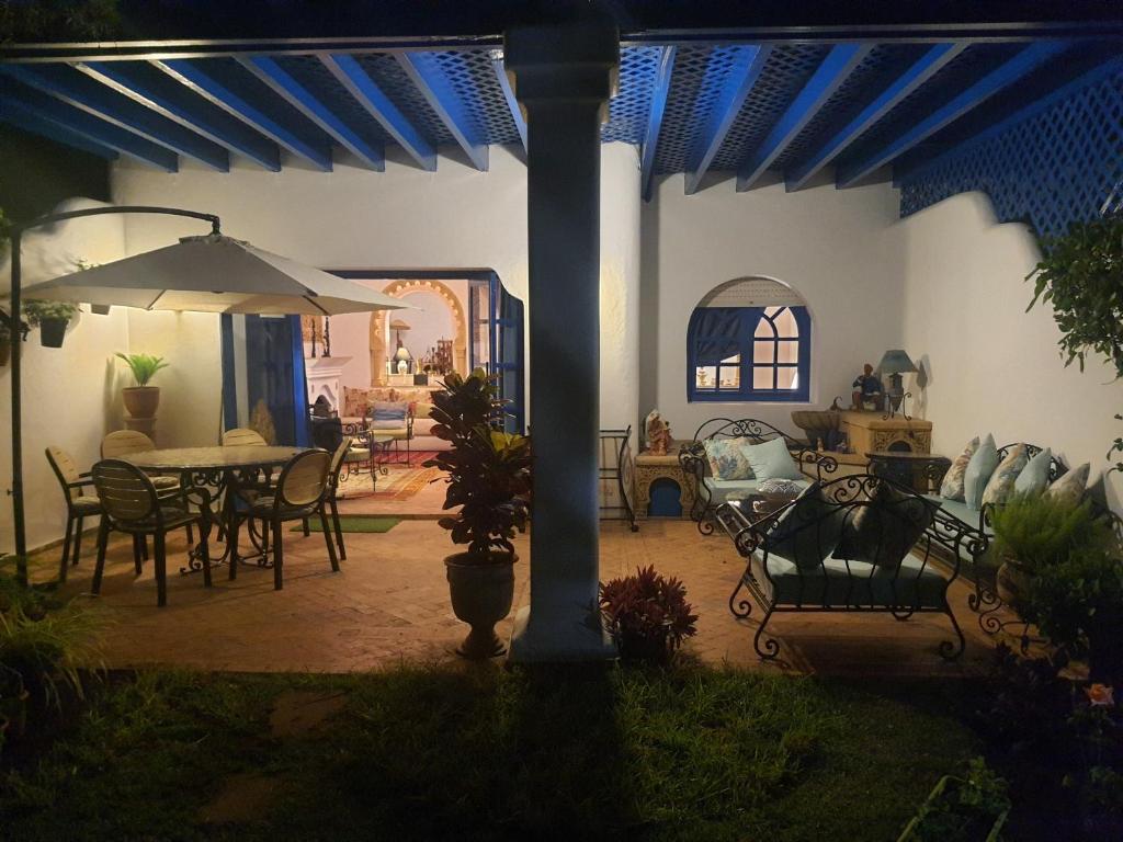 布兹尼盖Villa à Bouznika Bay-plage et golf的庭院配有桌椅和遮阳伞。