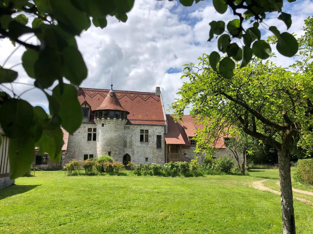 Saint-Martin-de-BoschervilleManoir de l'Aumônerie的一座古老的城堡,在绿地中设有红色屋顶