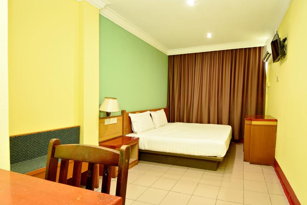 MukahMandarin Inn by Glex的酒店客房配有一张床铺和一张桌子。