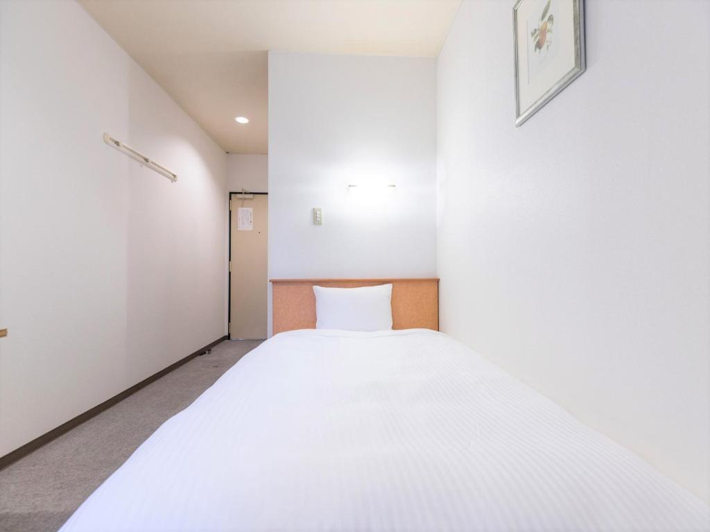 伊势崎市Hotel Isesaki East的一间白色的小房间,里面设有一张床