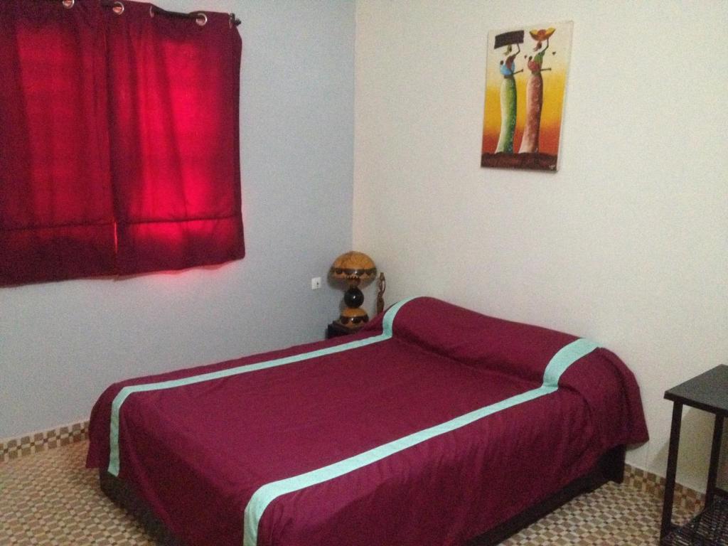瓦加杜古卡瓦纳酒店的一间卧室配有一张带红色窗帘的紫色床