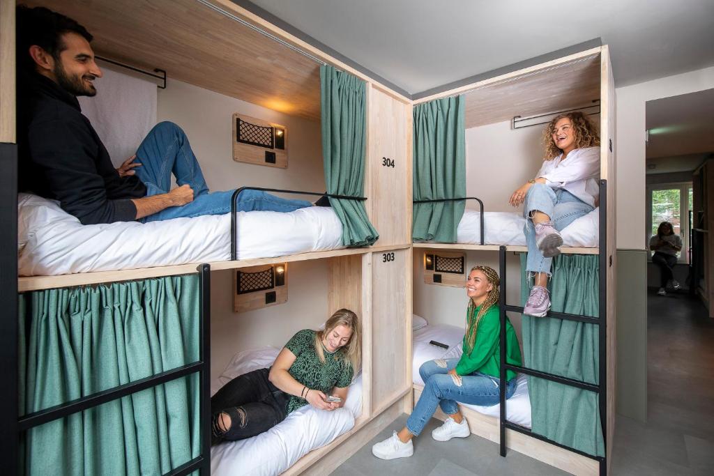 阿姆斯特丹The Bee Hostel的一群人坐在一个房间里双层床里