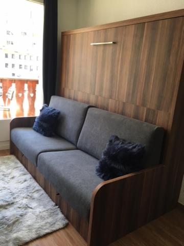 蒂涅studio cabine chalet club III entièrement rénové的一张沙发,上面有两个蓝色枕头