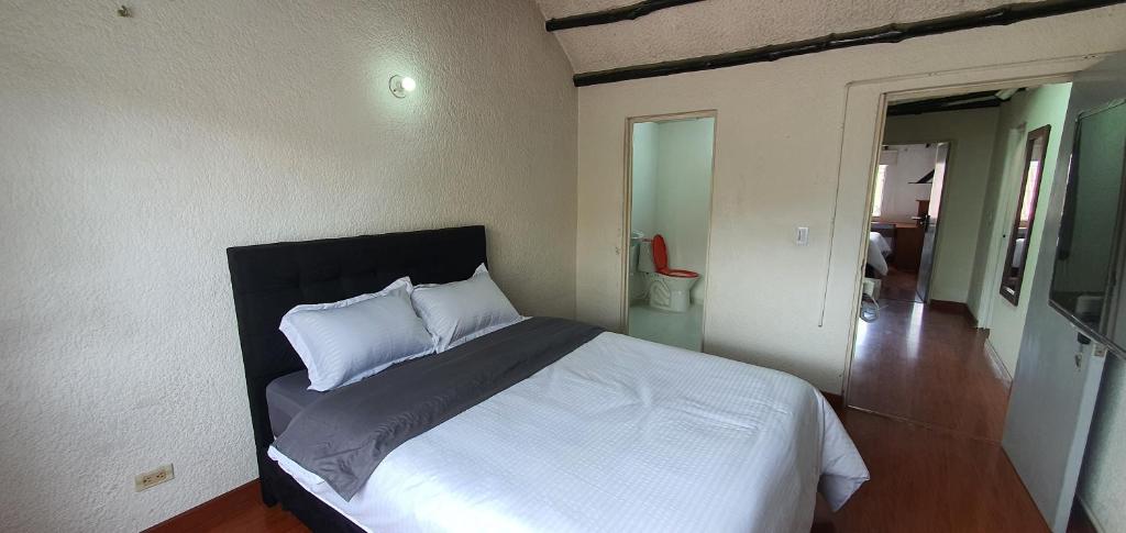 波哥大Portal Norte 170 ACOGEDORAS HABITACIONES CON TODOS LOS SERVICIOS的一间卧室配有带白色床单和枕头的床。