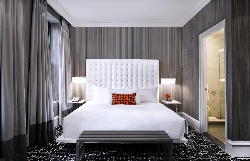 纽约摩登呢酒店的卧室配有一张大白色床和红色枕头
