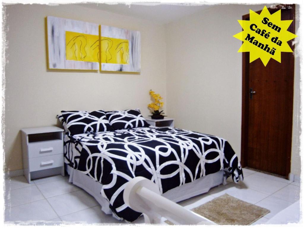 瓜拉派瑞Suítes de Setiba - HOSPEDARIA OCA RUCA的一间卧室配有一张带黑白色棉被的床