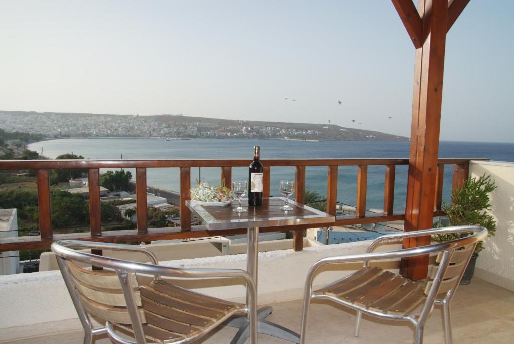 锡蒂亚海湾景公寓的阳台上的桌椅和一瓶葡萄酒
