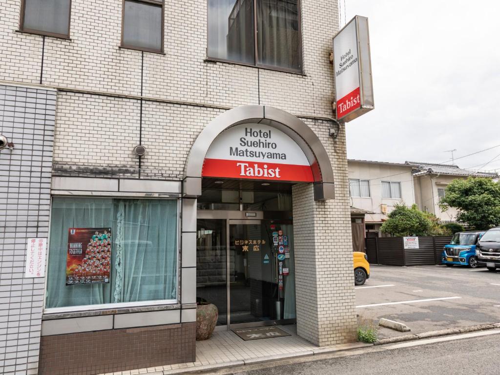 松山Tabist Business Hotel Suehiro Matsuyama的建筑前有标志的商店