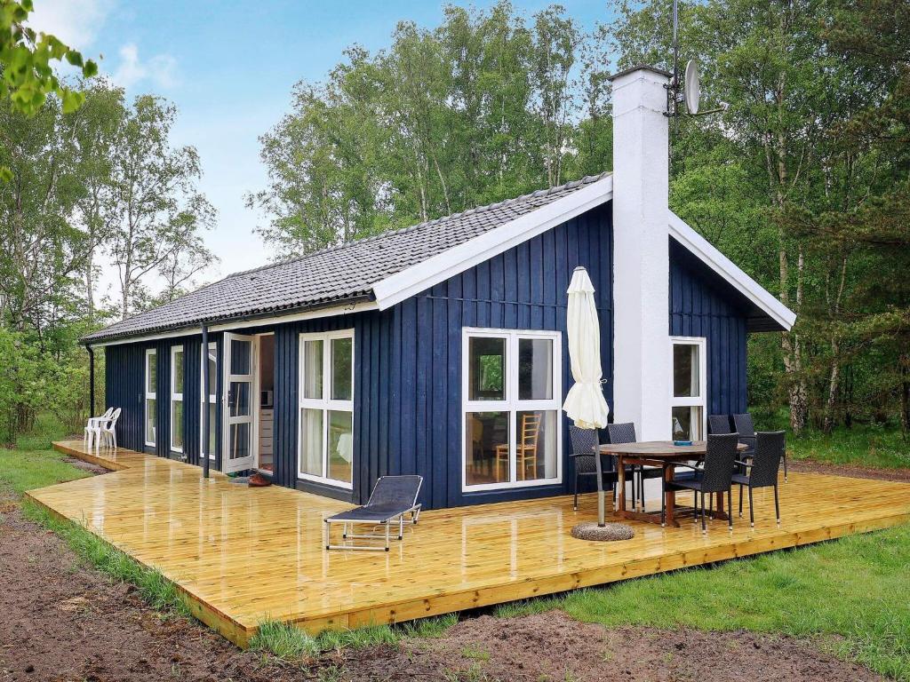 莱斯Holiday home Læsø LIII的蓝色的房子,设有甲板和桌子