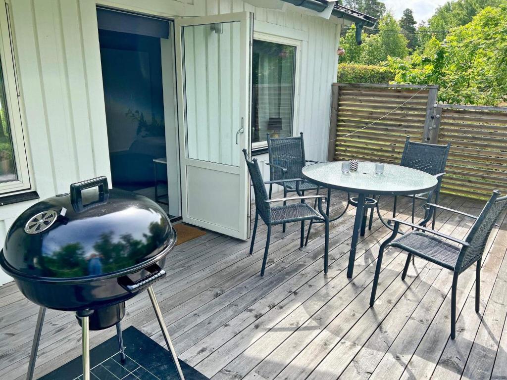 韦姆德Holiday home VÄRMDÖ V的甲板上的烧烤架,配有椅子和桌子