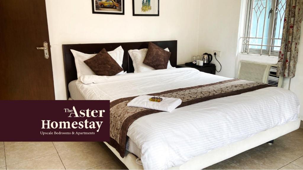 加尔各答The Aster Homestay - Bedrooms & Apartments的一间卧室配有一张大床,配有白色床单和棕色枕头