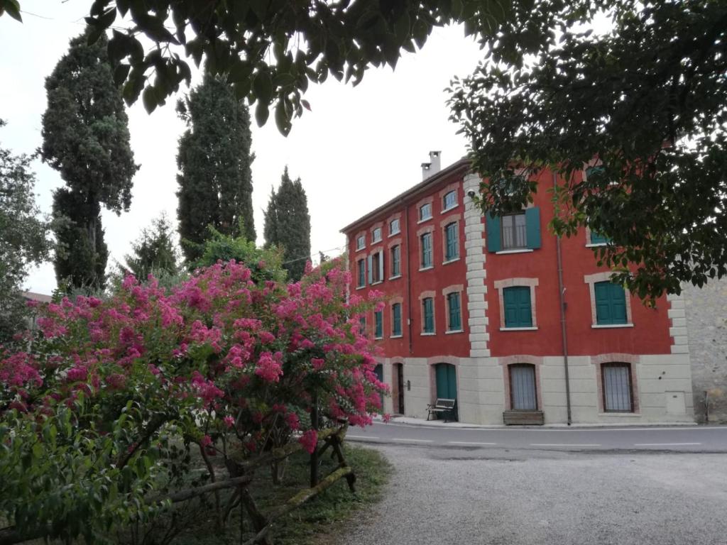 Marano di ValpolicellaMaregnago Relais的红砖建筑,前面有粉红色的花