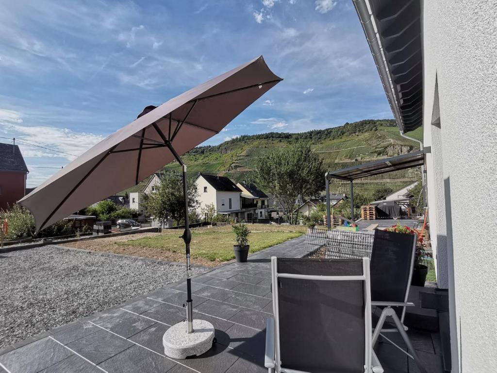 贝尔恩卡斯特尔-库斯Sonnenufer Apartment & Moselwein II的天井上配有遮阳伞和2把椅子