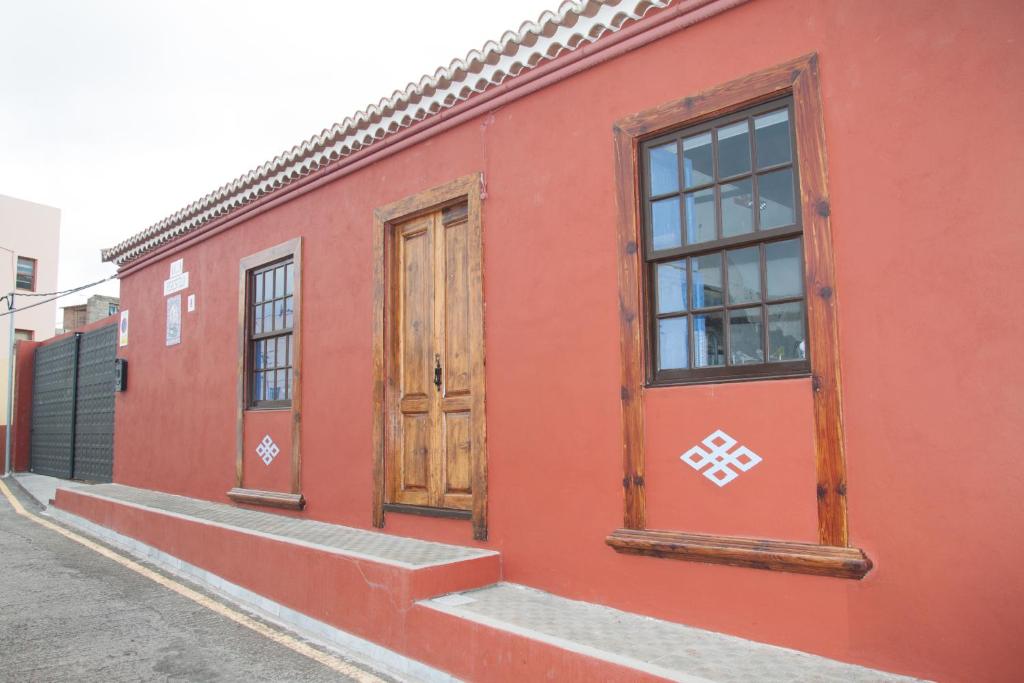 Los SaucesVilla Perestelo的红色的建筑,设有两扇窗户和一扇门