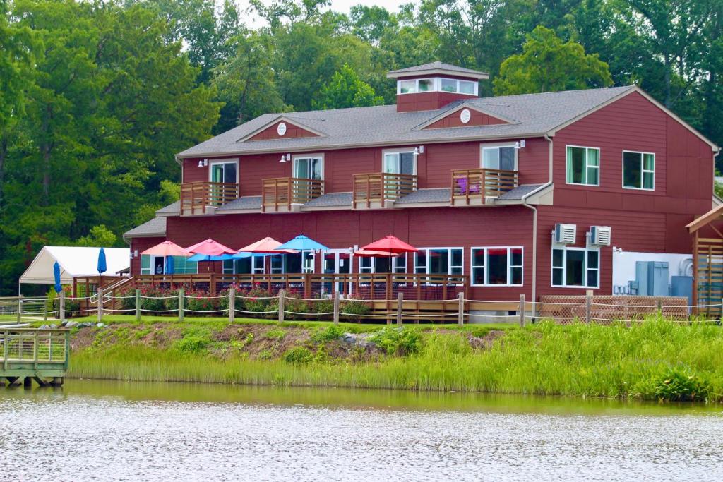SurrySurry Seafood Company的河边一座红色的大房子,配有桌子和遮阳伞