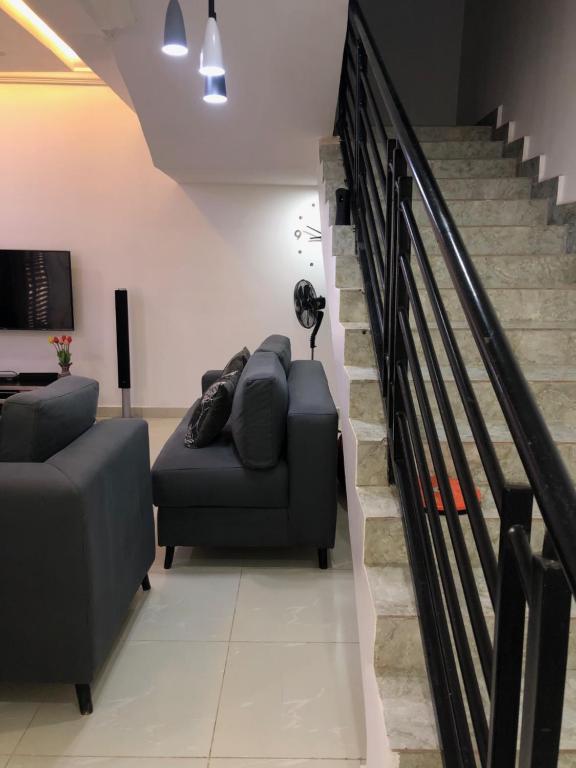阿布贾Entire Serviced Two bedroom duplex Abuja - 24hr WIFI, POWER, OFFICE, FULL KITCHEN的带沙发和楼梯的客厅