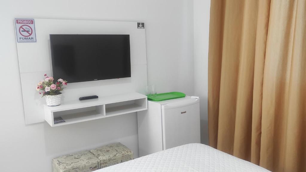 乌巴图巴Mar dos Sonhos Suítes的卧室配有一台电视,位于白色的墙壁上,配有床