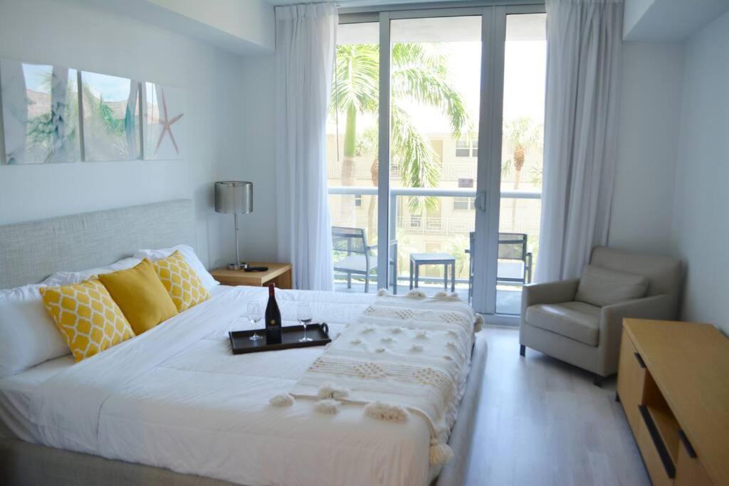 哈兰代尔海滩Lovely 1 Bedroom condo 1 Bath w patio & kitchen的卧室配有一张白色大床和一把椅子