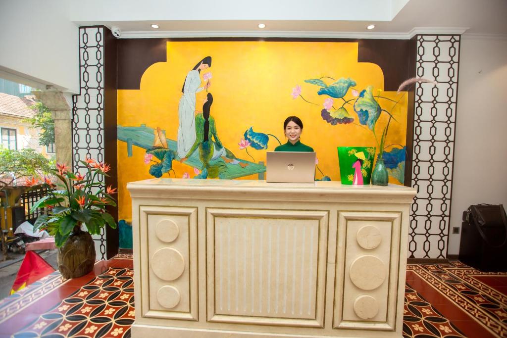 河内Hanoi Center Silk Boutique Hotel & Travel的一位女士坐在一张桌子上,手提电脑